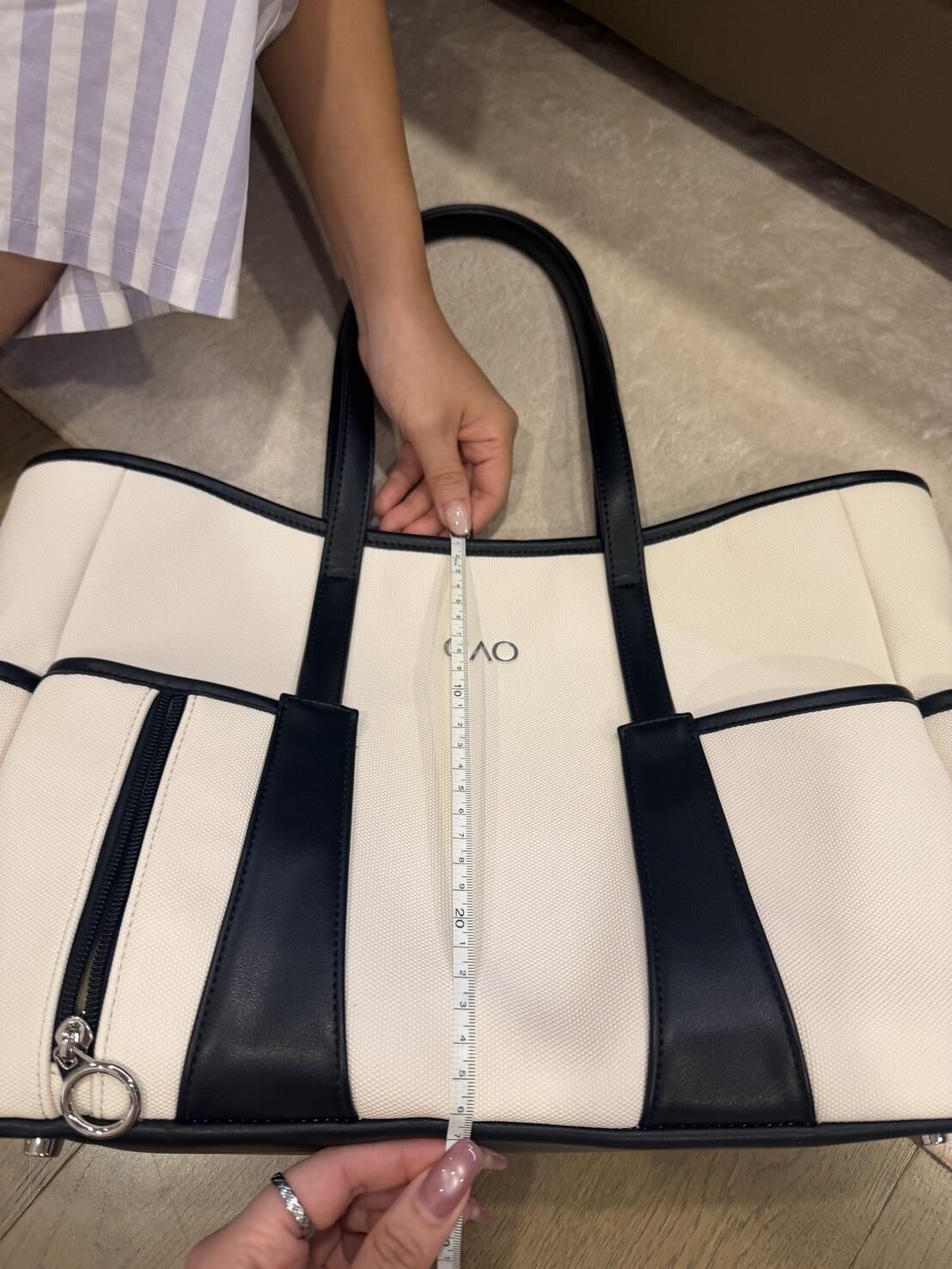 A tape measure run down the front of the Black / Ivory tote, rim to base