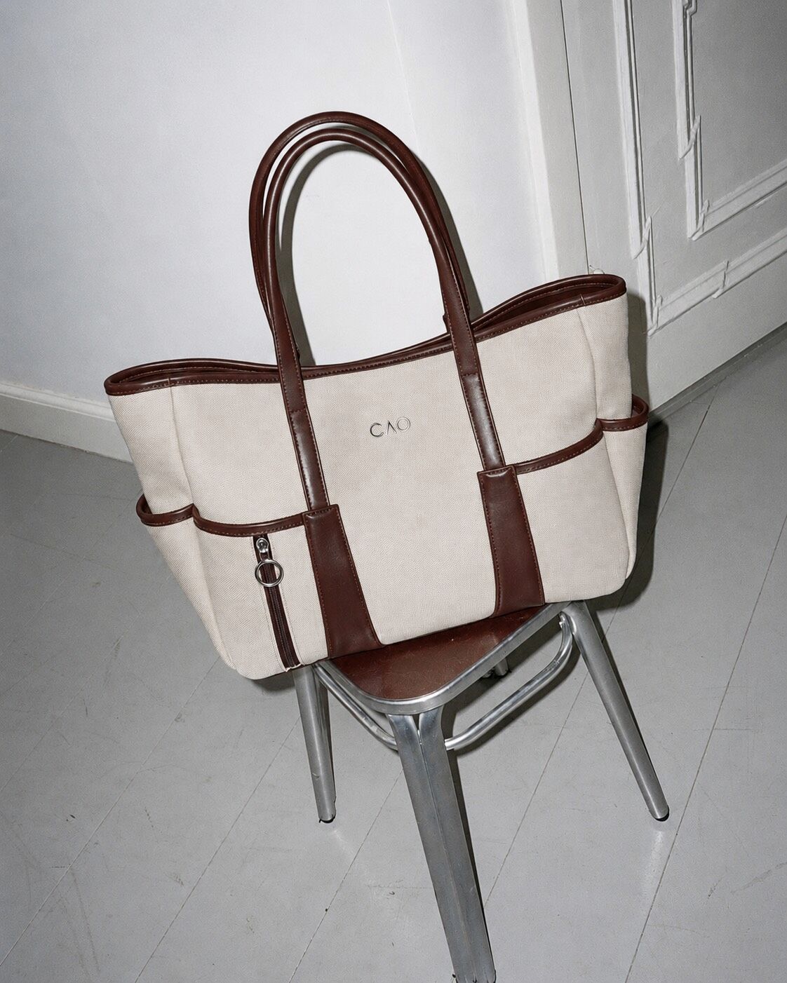 The CAO Tote in Brown / Ecru on a metal chair